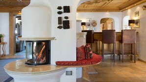 A modern interior with a fireplace, seating area, and bar. - Hotel Angela (Lech am Arlberg)