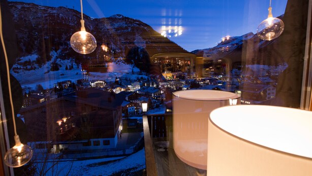 A view from a window overlooking a snowy town with mountains in the background. - Hotel Angela (Lech am Arlberg)