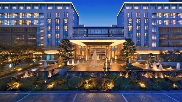Un hotel moderno con un patio central que cuenta con fuentes y senderos bien iluminados.