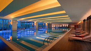 Una piscina interior moderna con asientos escalonados y vistas al exterior.