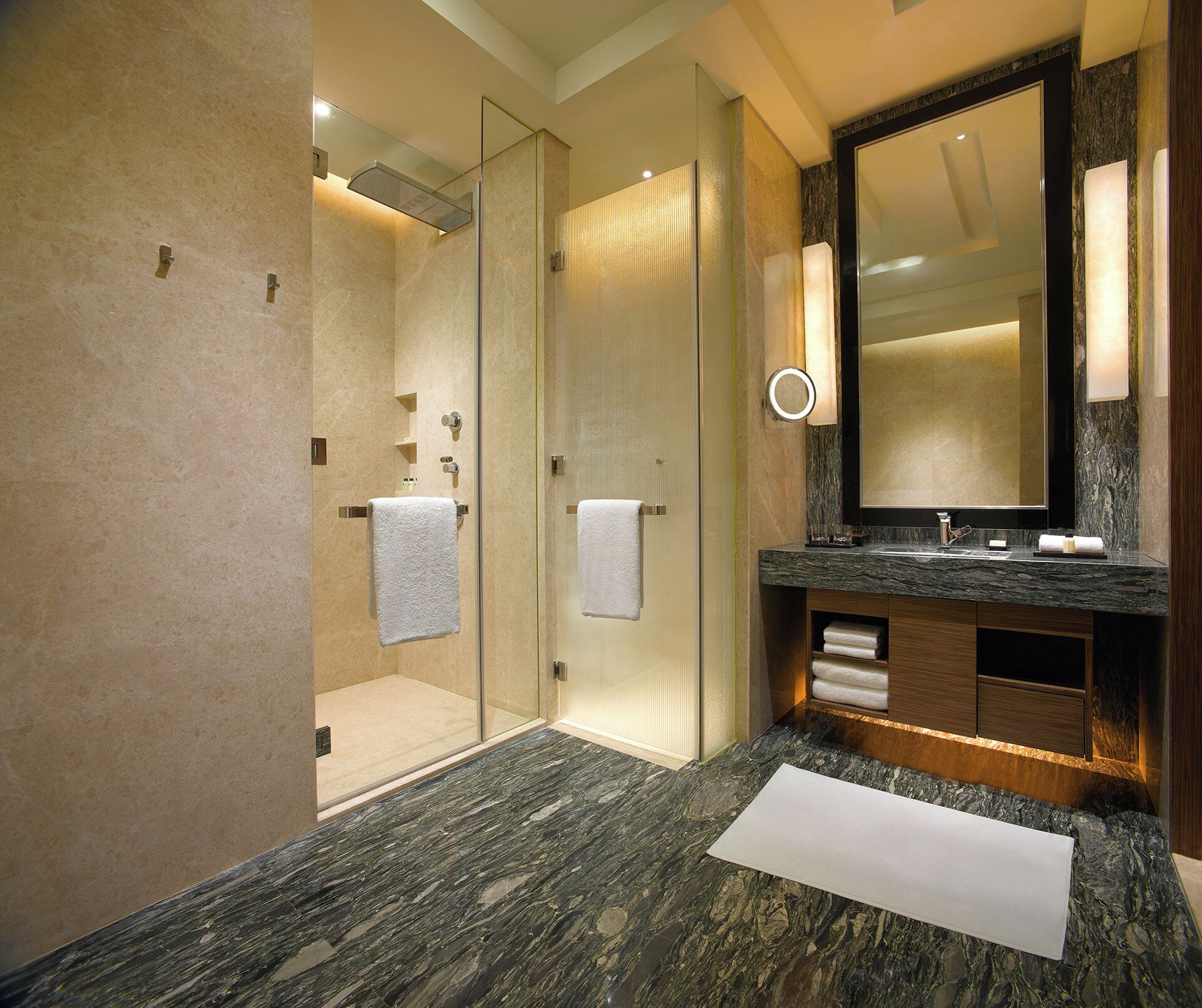 Un baño moderno con ducha acristalada, lavabo de mármol y un espejo grande.