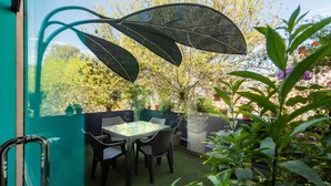 A glass-enclosed patio with a table and chairs, surrounded by potted plants and a view of trees and buildings. - Dreams Boutique Hotel (Arequipa)