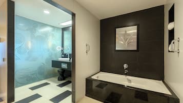 Un baño moderno con una bañera negra, un espejo grande y un papel tapiz estampado.