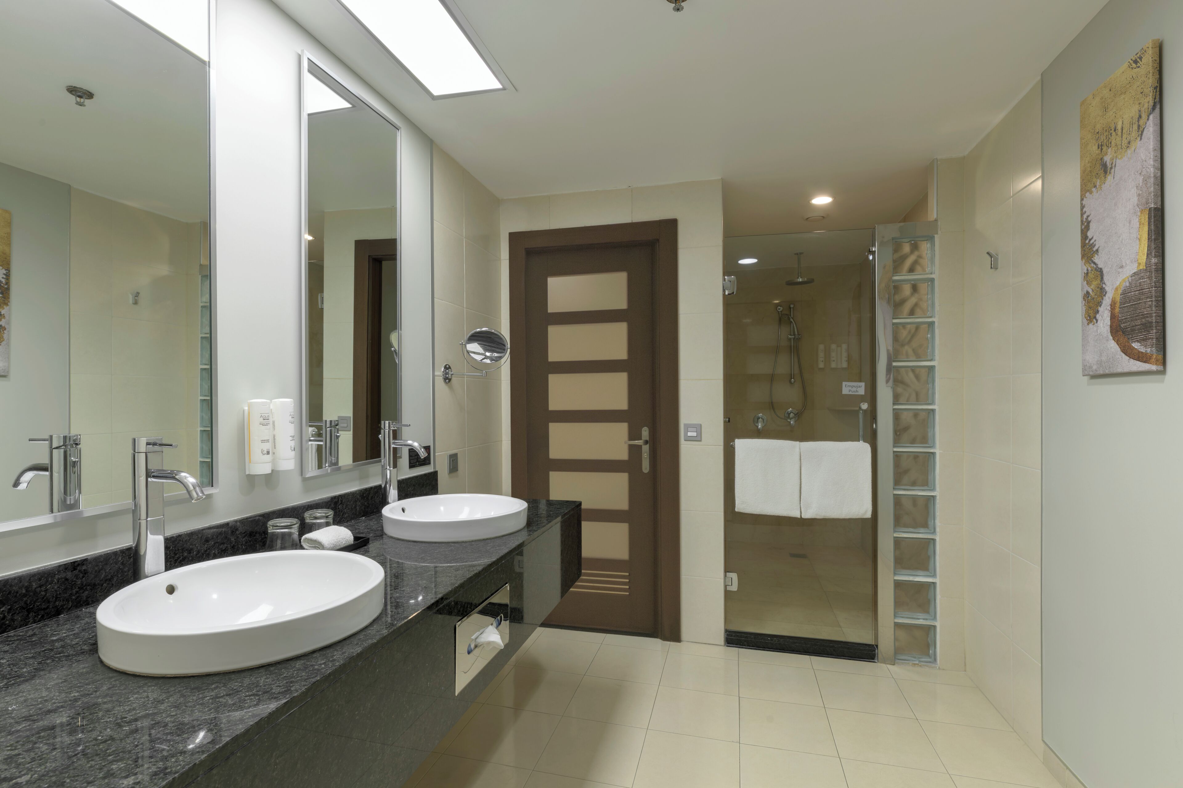 Un baño moderno con dos lavamanos, un espejo grande y una cabina de ducha de vidrio.
