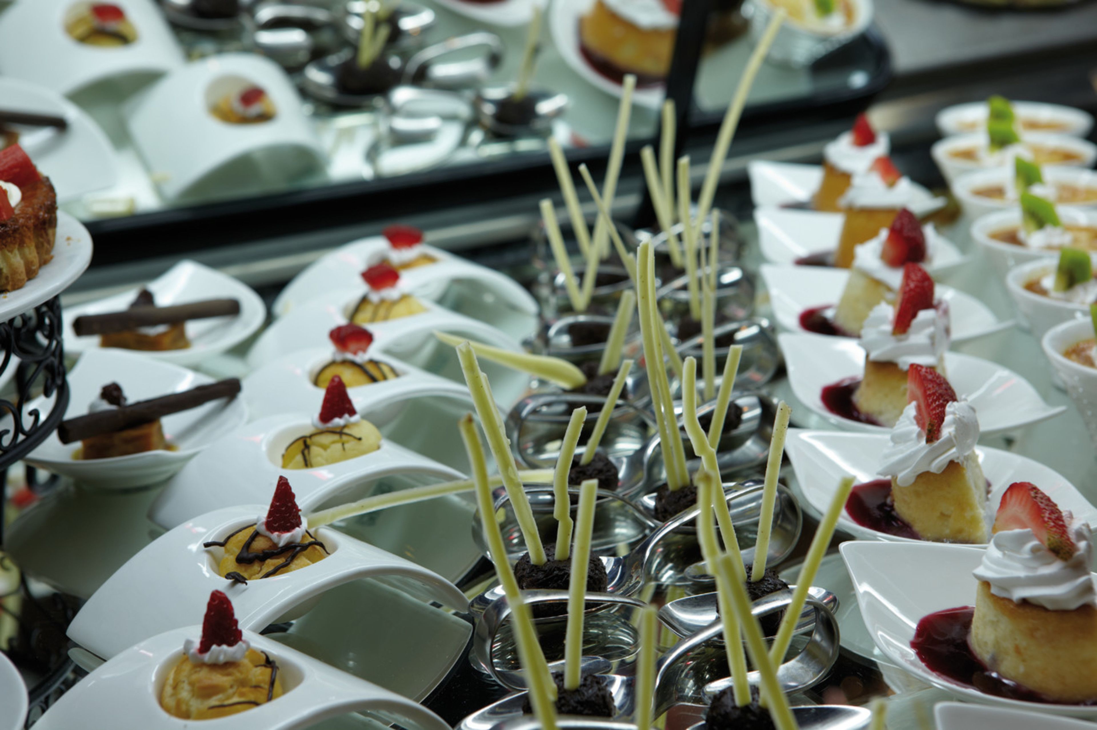 Variedad de postres dispuestos en platos, algunos con fresas y goteo de chocolate.