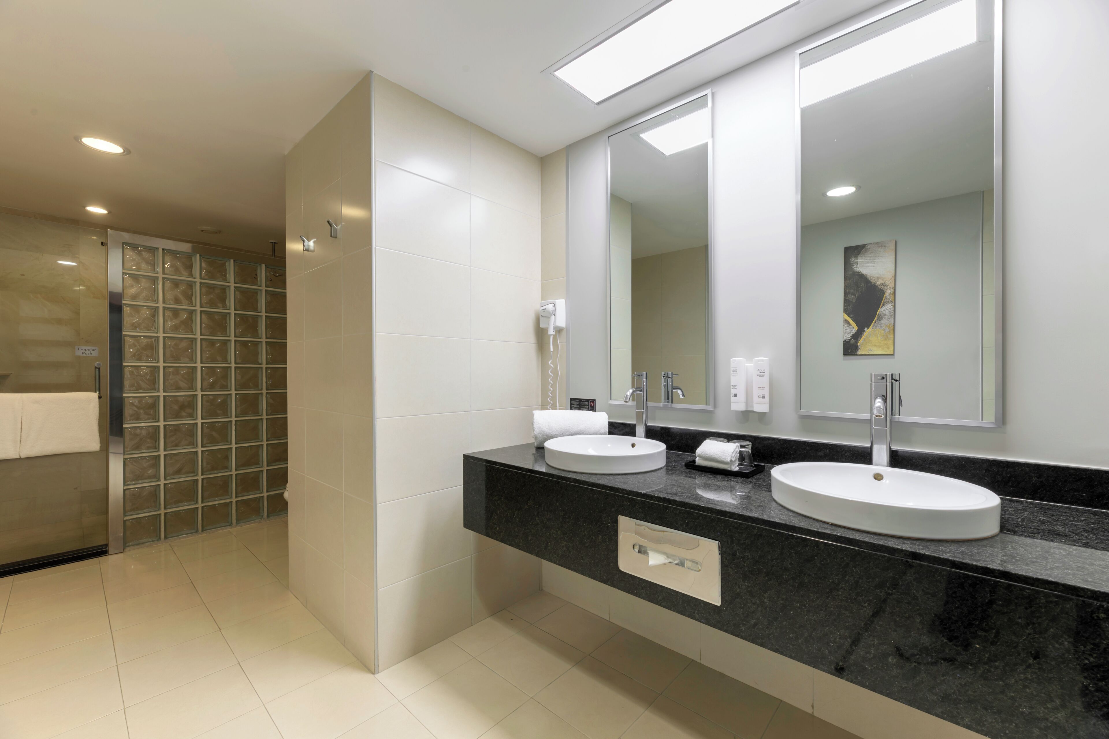 Un baño moderno con dos lavamanos, un espejo grande y una zona de ducha.