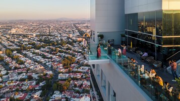 Et højt hotel med en glasbalkon med udsigt over bybilledet.