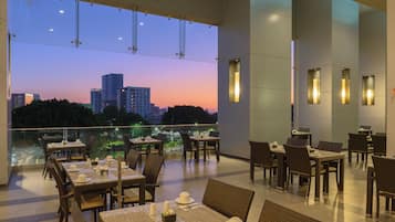 Ein Restaurant mit gedeckten Tischen, Blick auf die Stadt und modernen Leuchten.