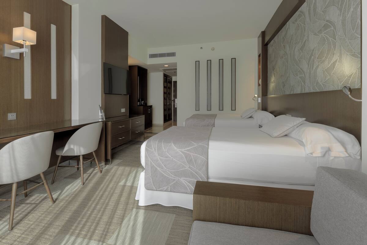 Une chambre d’hôtel moderne équipée d’un lit, d’un bureau, d’une chaise et d’un téléviseur.