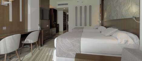 A modern hotel room with a bed, a desk, a chair, and a television.