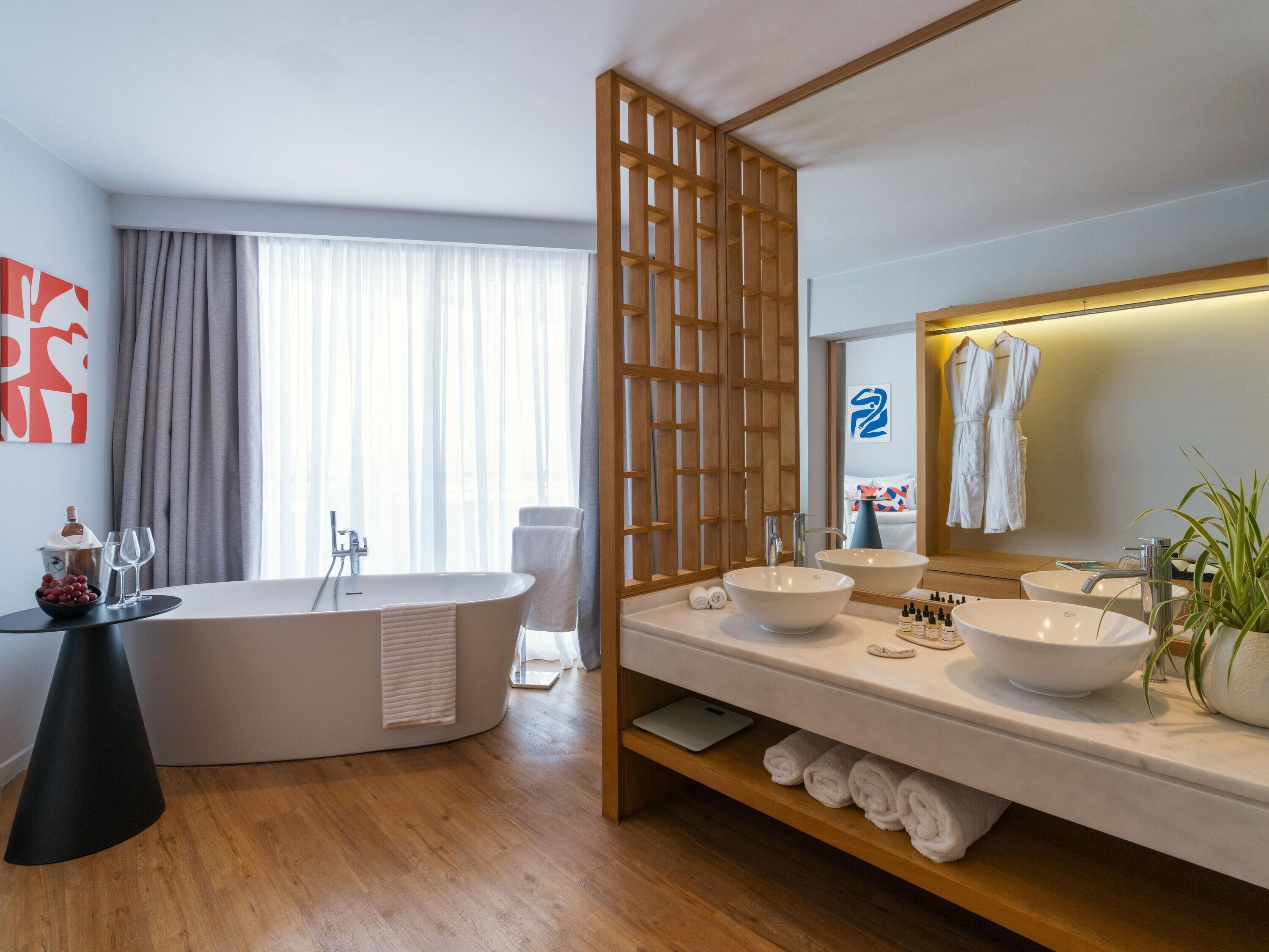 Un baño moderno con una bañera independiente, dos lavamanos y un espejo grande.