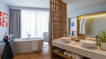 Un baño moderno con una bañera independiente, dos lavamanos y un espejo grande.