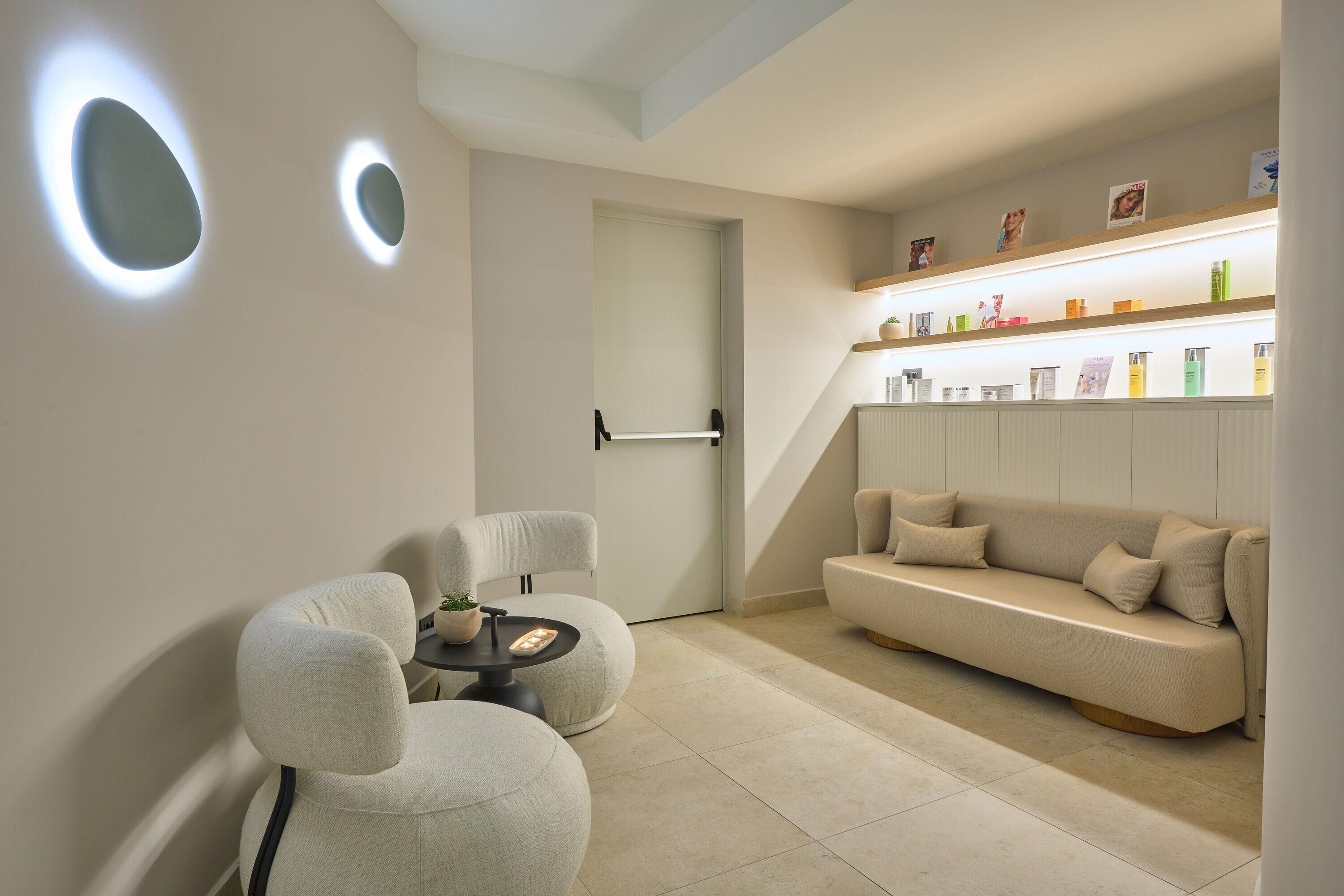 A modern living room with a sofa, chairs, a coffee table, and a bookshelf with various items.