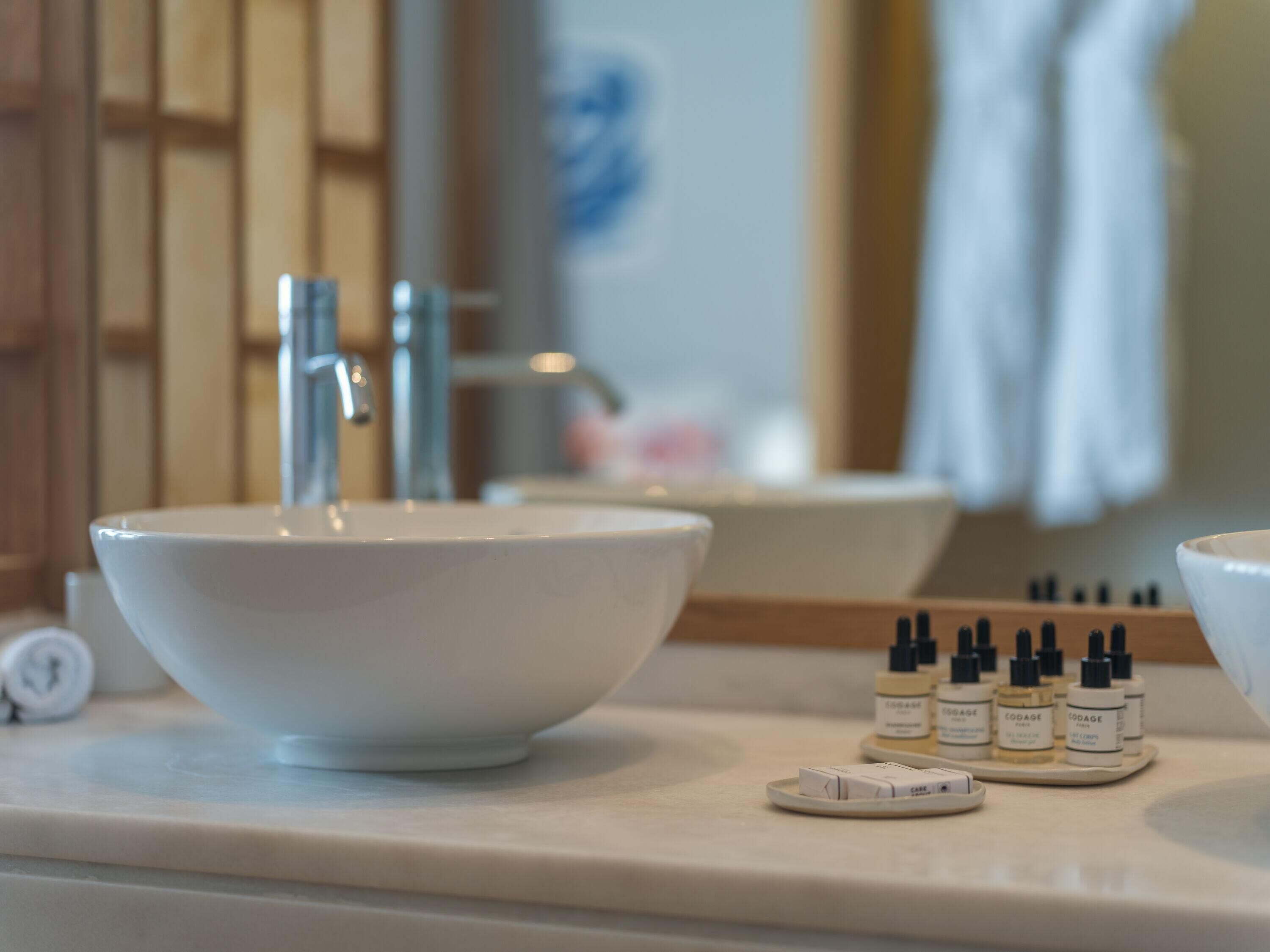Un baño con un lavamanos grande de color blanco, un espejo y una encimera con productos para el cuidado de la piel.