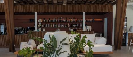 A modern living area with a sofa, potted plants, and a bar area in the background.