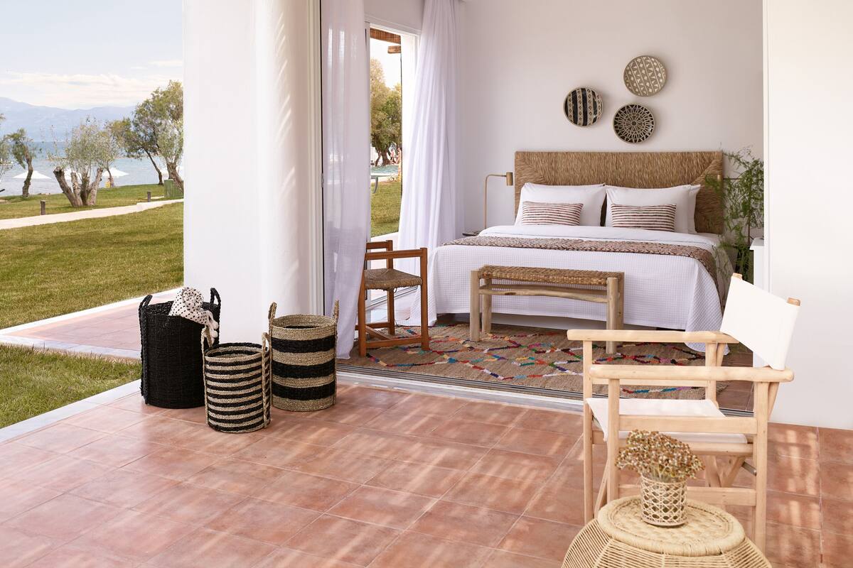 A bedroom with a bed, a chair, a small table, and a view of the outdoors.