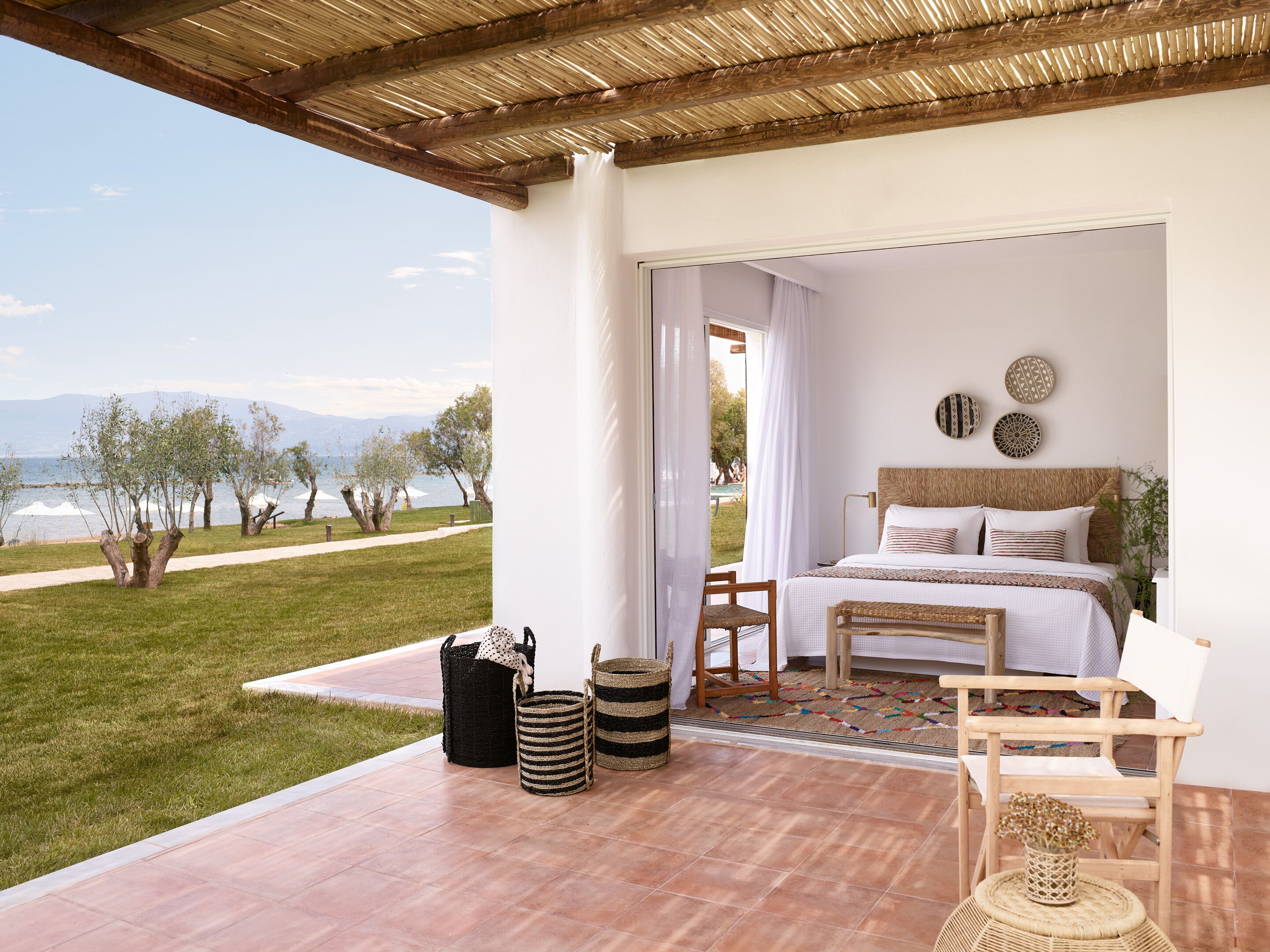 A bedroom with a bed, a chair, a small table, and a view of a lake.