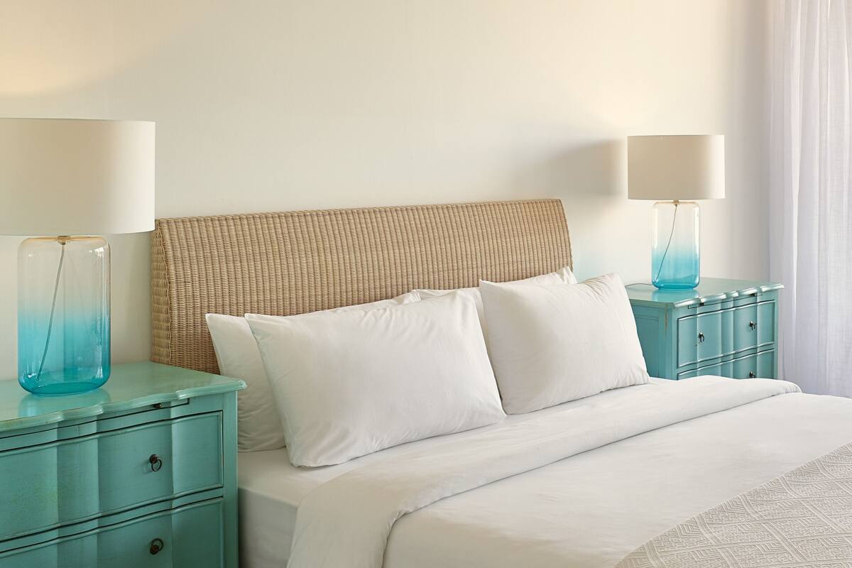 A hotel room with a bed, two nightstands, and a lamp on each side.