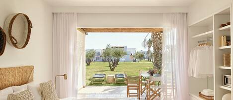 A bedroom with a bed, a bedside table, a wardrobe, and a view of an outdoor garden.