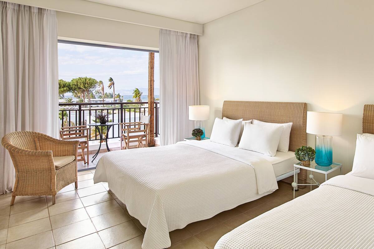 A hotel room with a balcony, a bed, a chair, and a table.