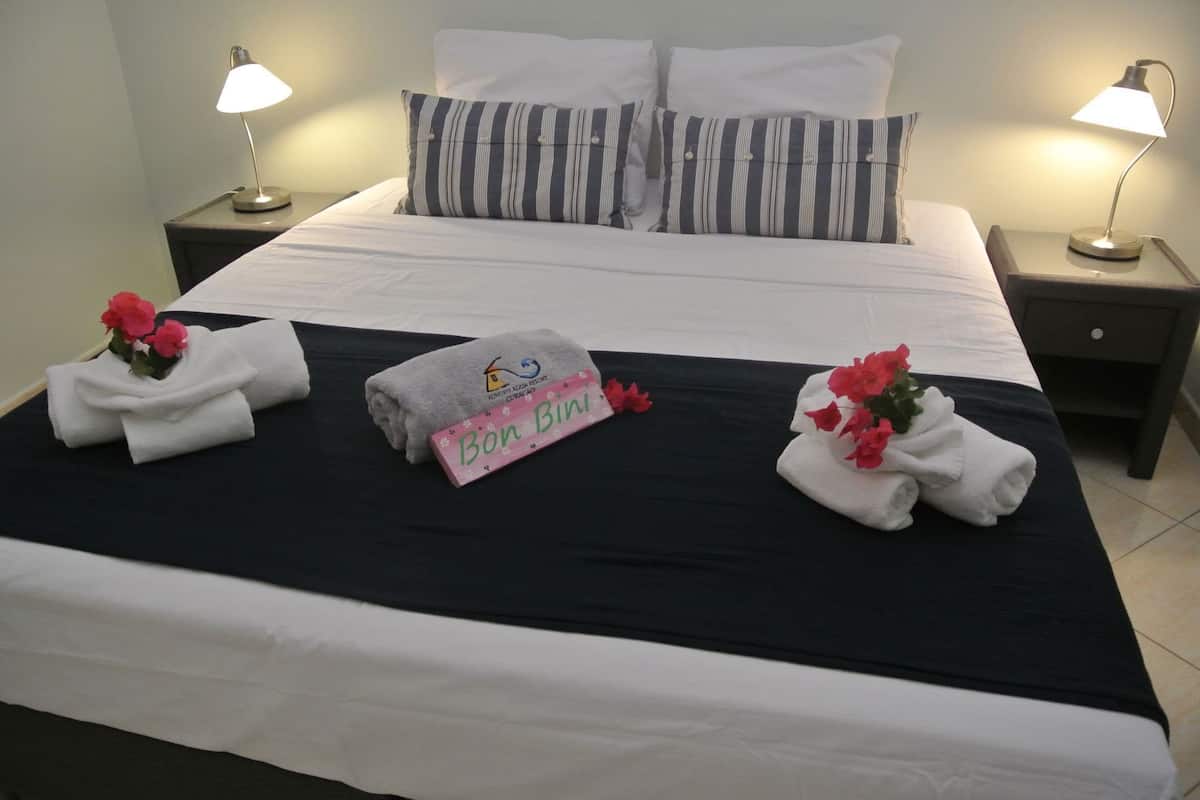 A neatly made bed with white linens, striped pillows, and two bedside lamps.