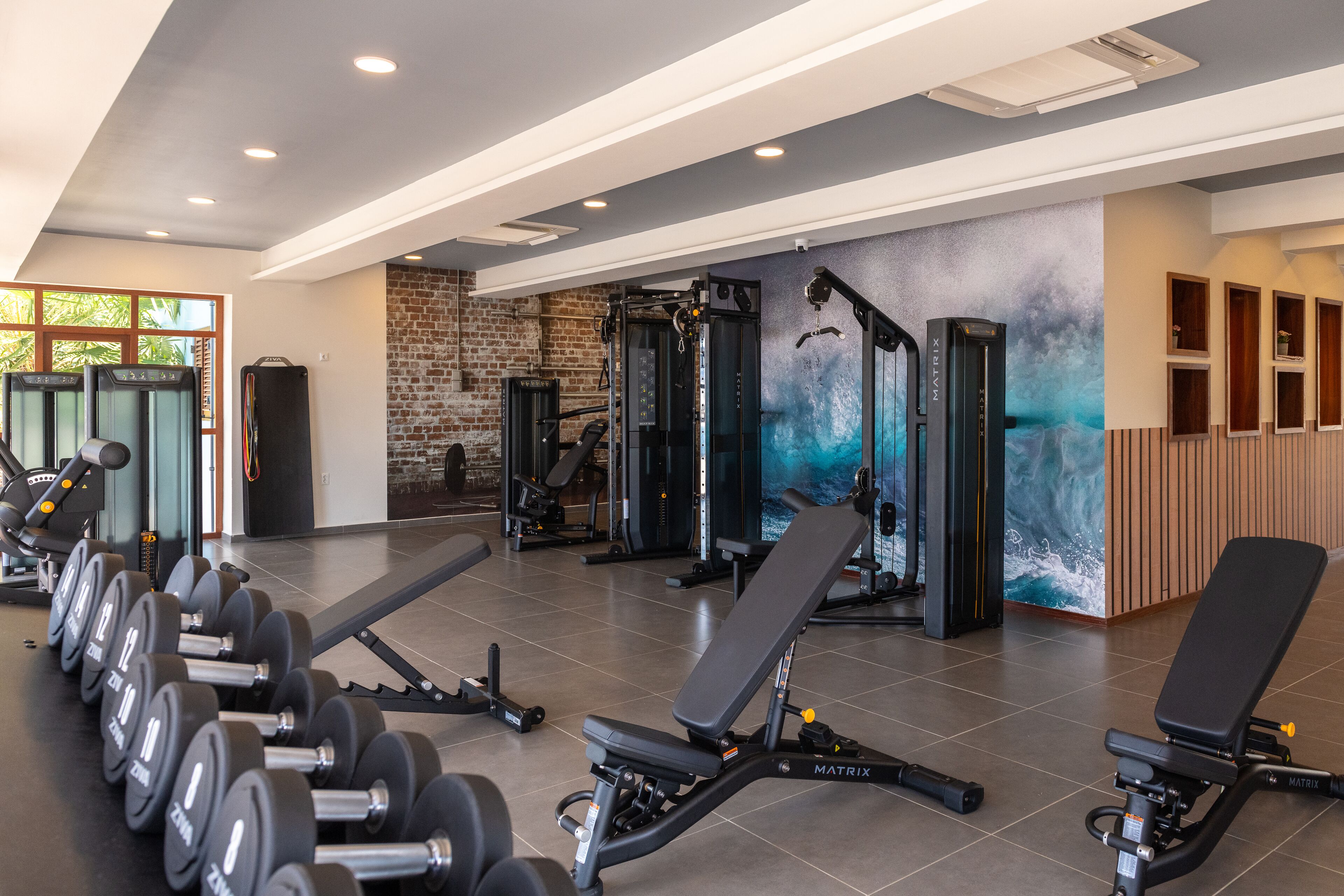 Una palestra con attrezzature per l'allenamento con i pesi, panche e un murale.
