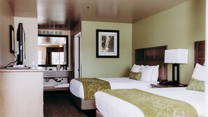 Habitación de hotel con dos camas, un escritorio, un espejo y un cuadro en la pared.