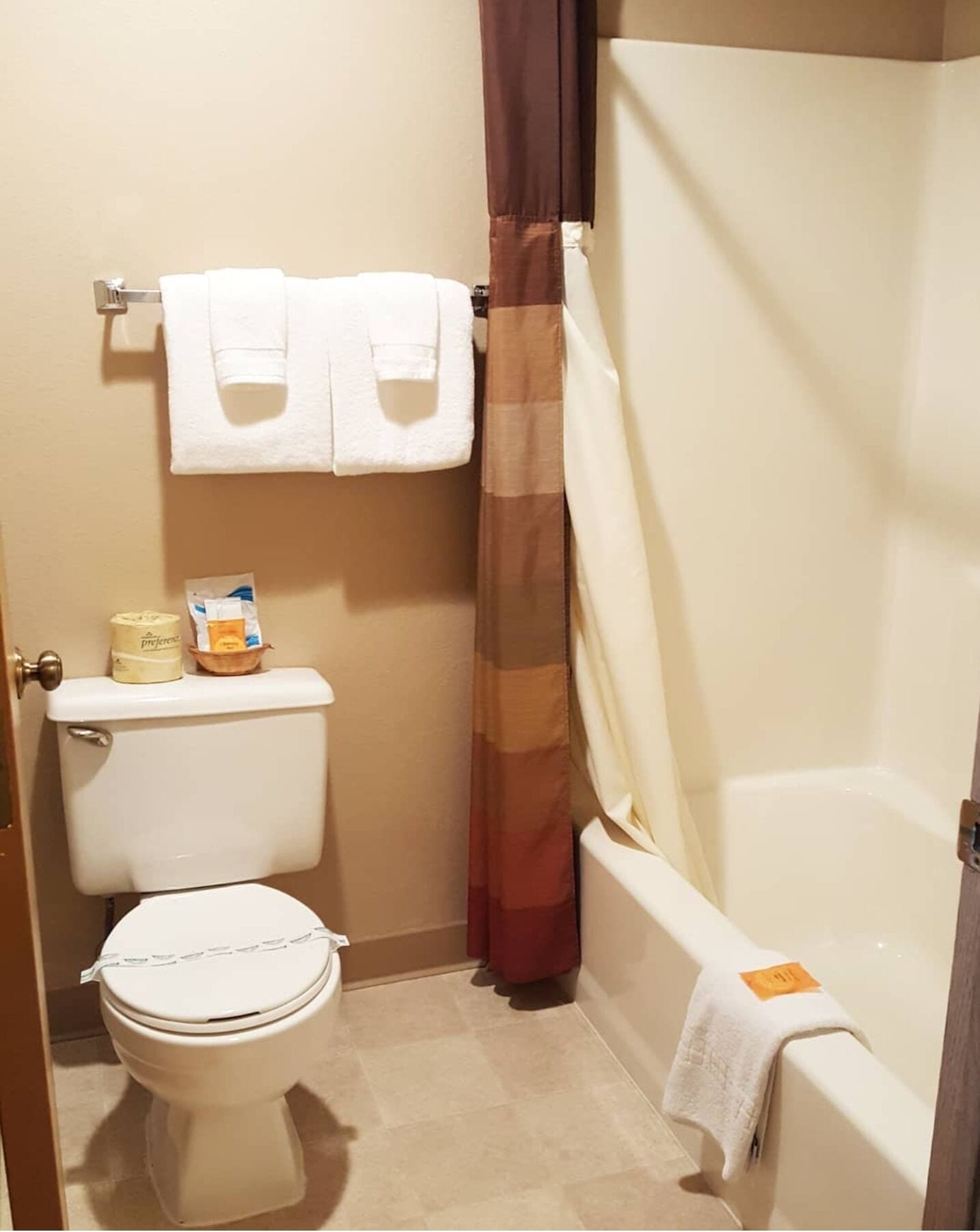 A small bathroom with a toilet, a bathtub, and a shower curtain.