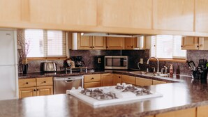 Una cocina moderna con armarios de madera, encimera de granito, microondas integrado, estufa a gas y cafetera.