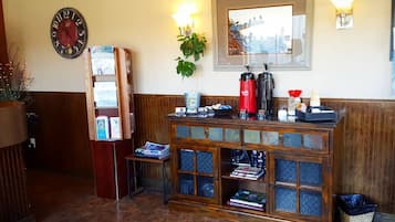 Un comptoir d’accueil avec une horloge, une plante et un tableau encadré au mur.