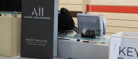 Un mostrador de recepción con un cartel que dice "ACCOR - LIVE LIMITLESS" y "PRIORITY WELCOME".