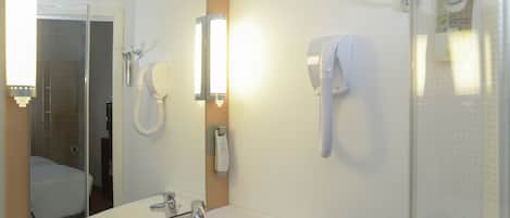 A bathroom with a white sink, a mirror, and two white hand dryers mounted on the wall.