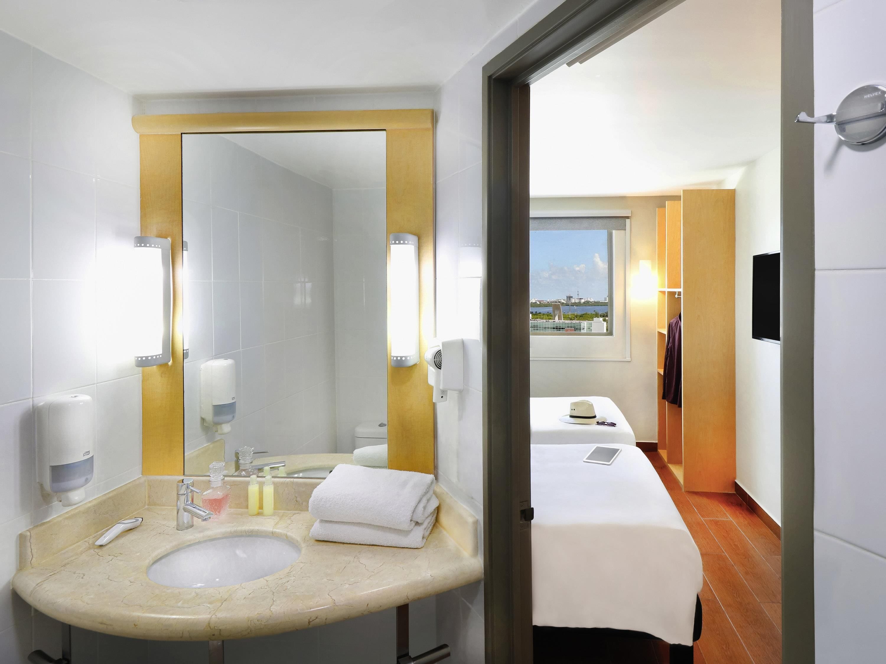 Een hotelbadkamer met een wastafel, spiegel en toiletartikelen.