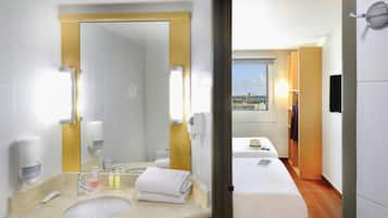 A hotel bathroom with a sink, mirror, and toiletries.