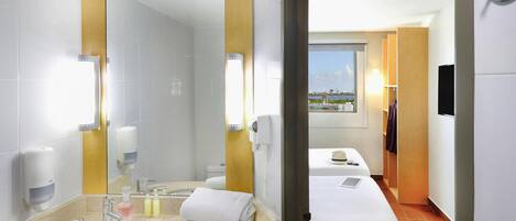 Een hotelbadkamer met een wastafel, spiegel en toiletartikelen.