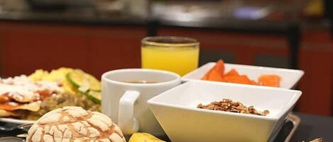 A tray with a banana, a bowl of granola, a cup of coffee, and a plate with a dumpling.
