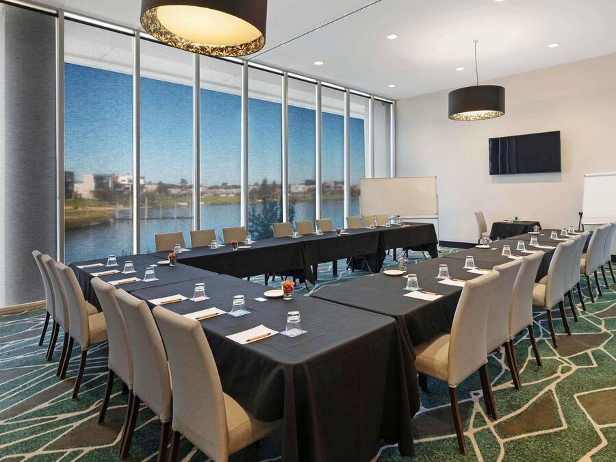 A conference room with a large table, chairs, a whiteboard, and a view of a body of water.