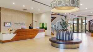 Zona de recepción con un mostrador de madera, un amplio espacio de asientos circulares y una escalera que lleva a pisos superiores.