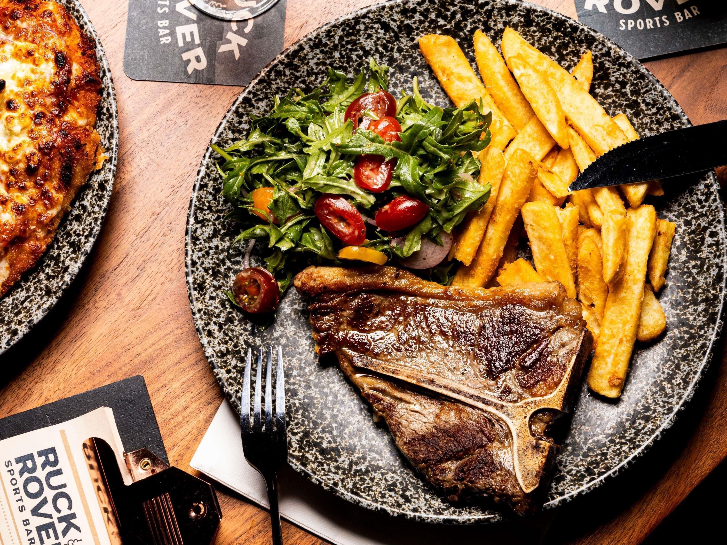 A plate with a steak, fries, and salad.