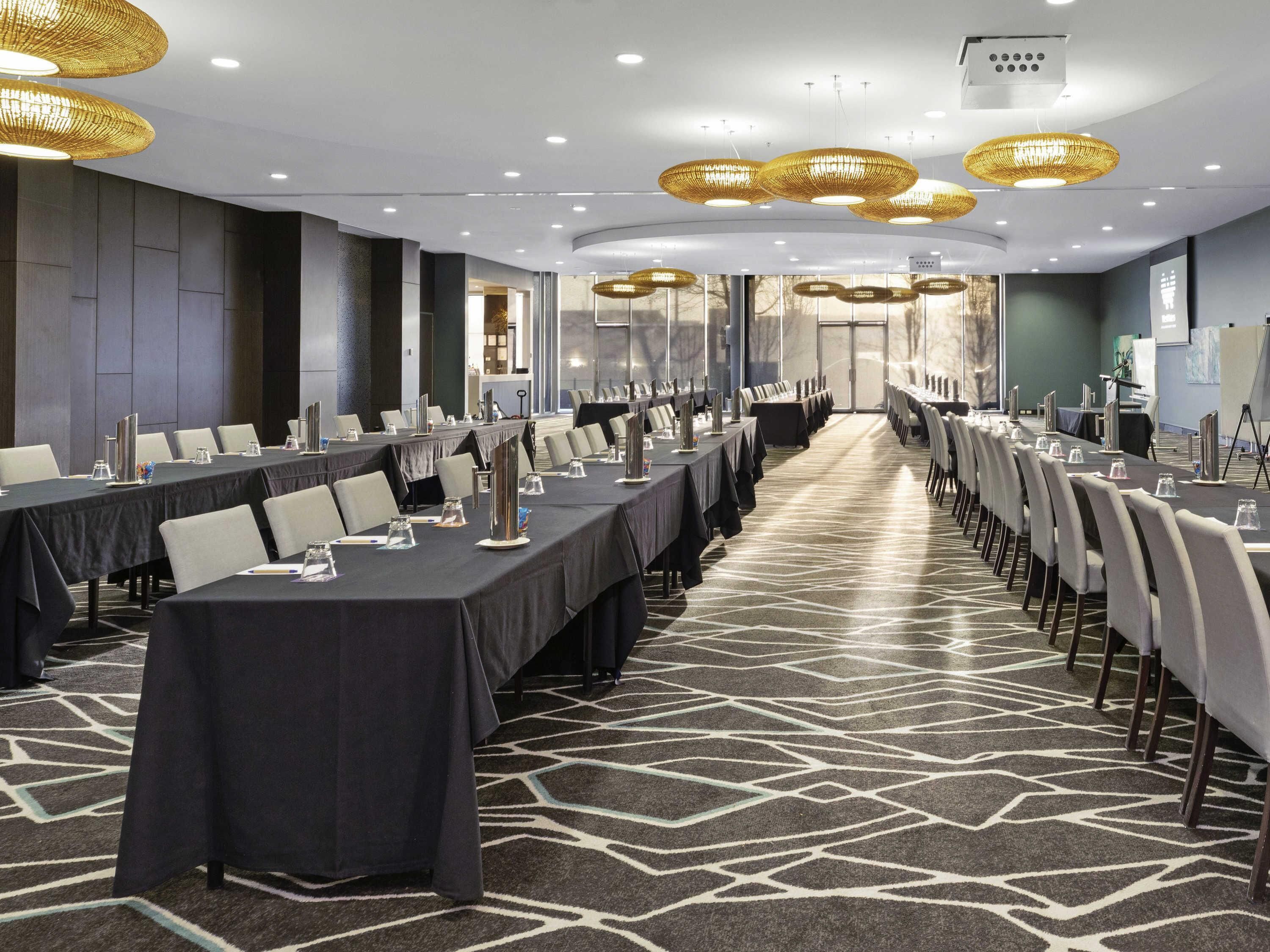 A conference room with long tables, chairs, and overhead lighting.