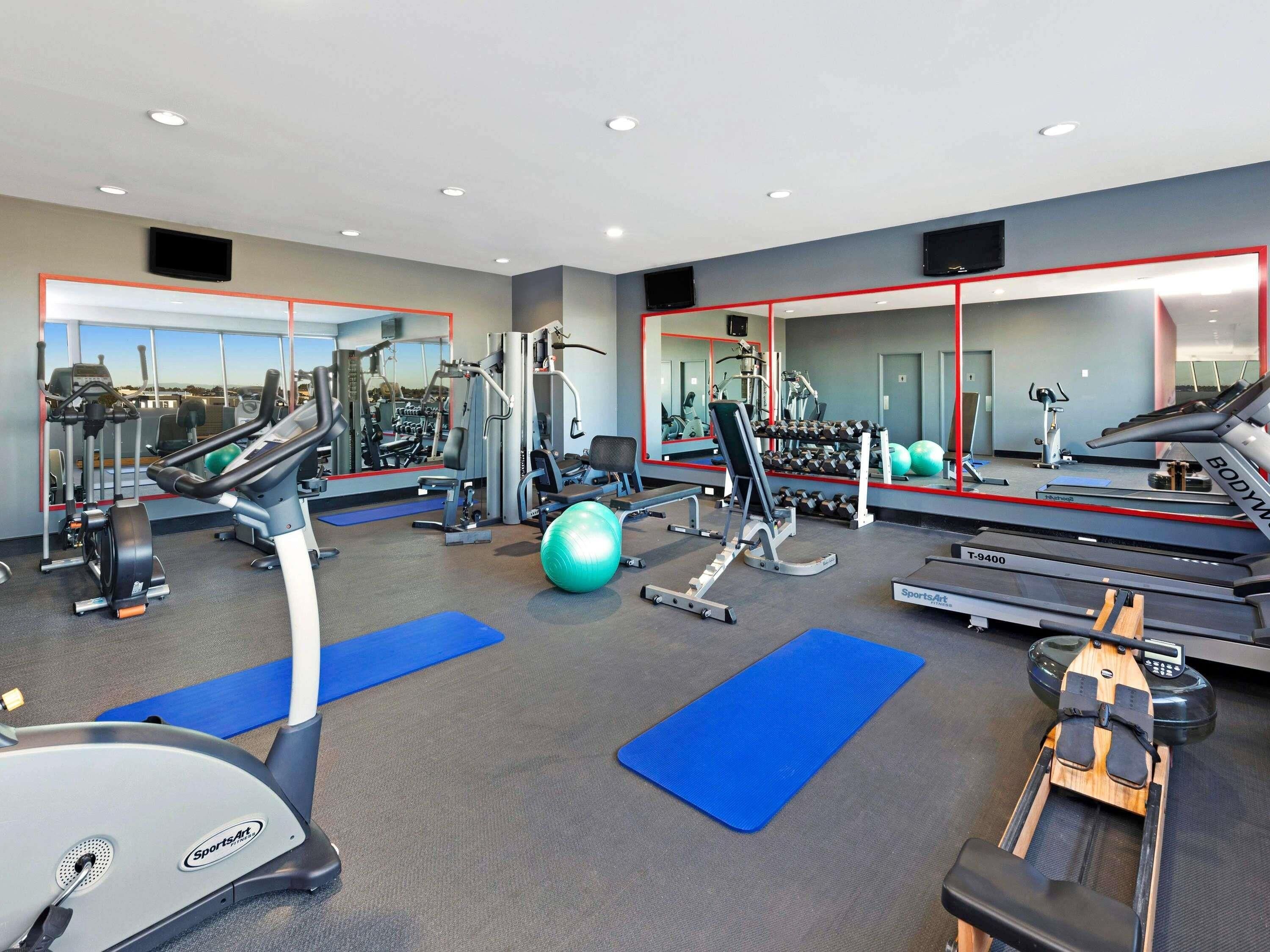 A gym with cardio equipment, weight machines, and exercise balls.