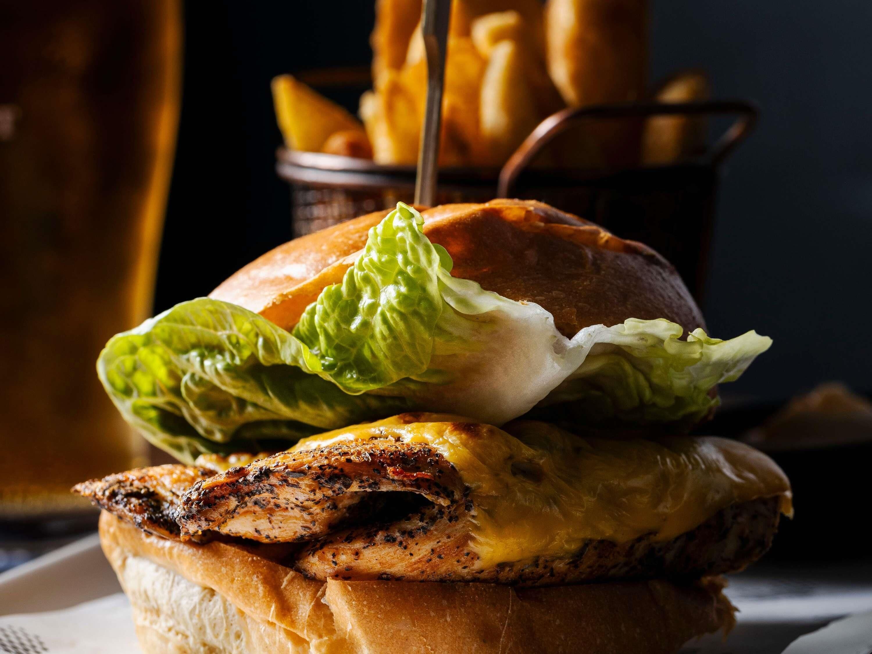 A sandwich with lettuce and a grilled chicken patty, accompanied by a side of fries.