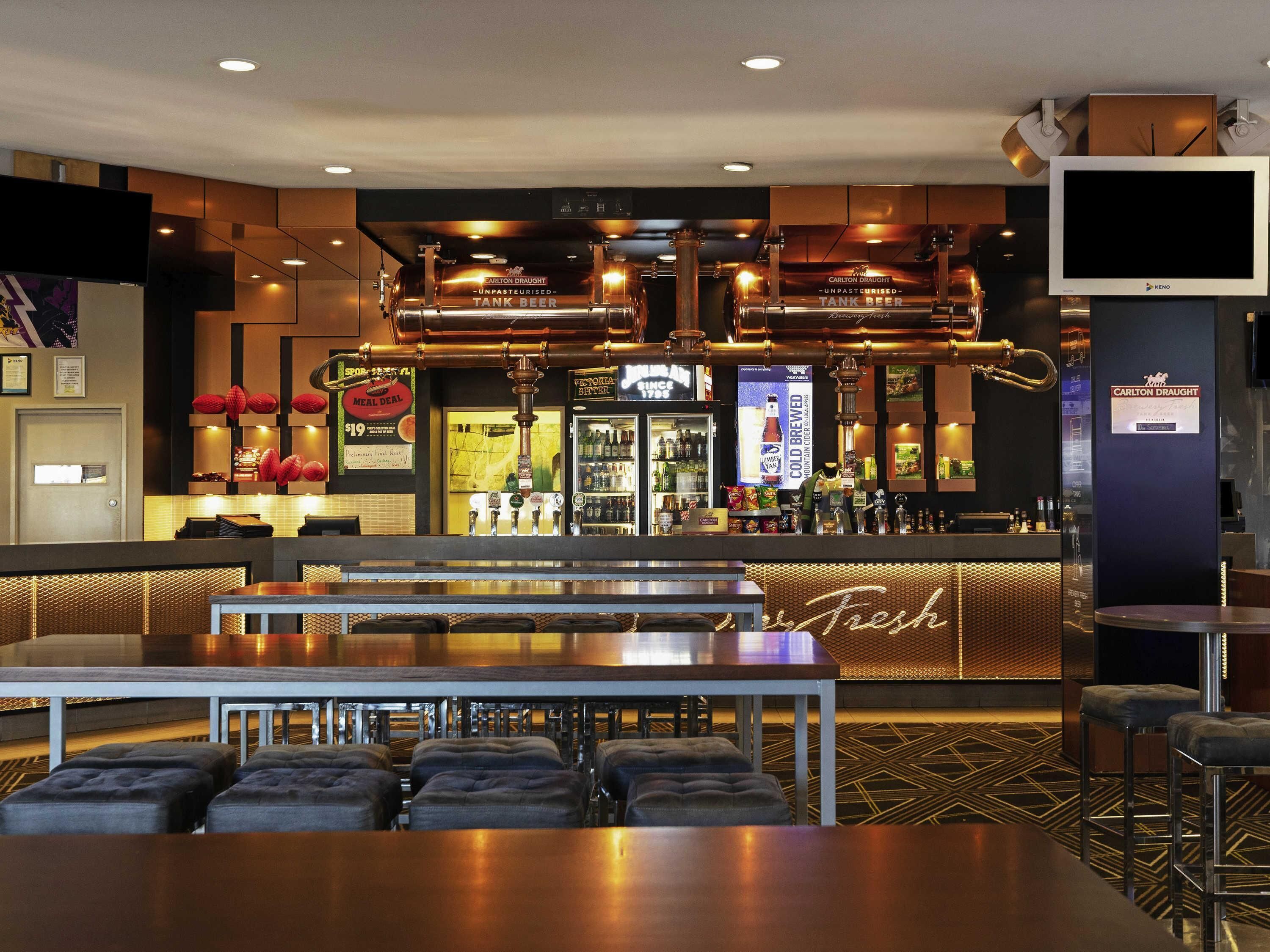 A bar area with stools, a counter, and a television screen.