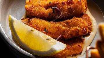 A plate with breaded and fried food items, a slice of lemon, and a small garnish.