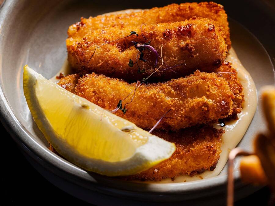 A plate with breaded and fried food items, a slice of lemon, and a small garnish.
