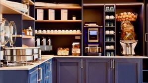 Une cuisine moderne dotée d’appareils électroménagers intégrés, notamment une machine à café et une bouilloire, ainsi que d’une variété d’ustensiles de cuisine et d’accessoires.