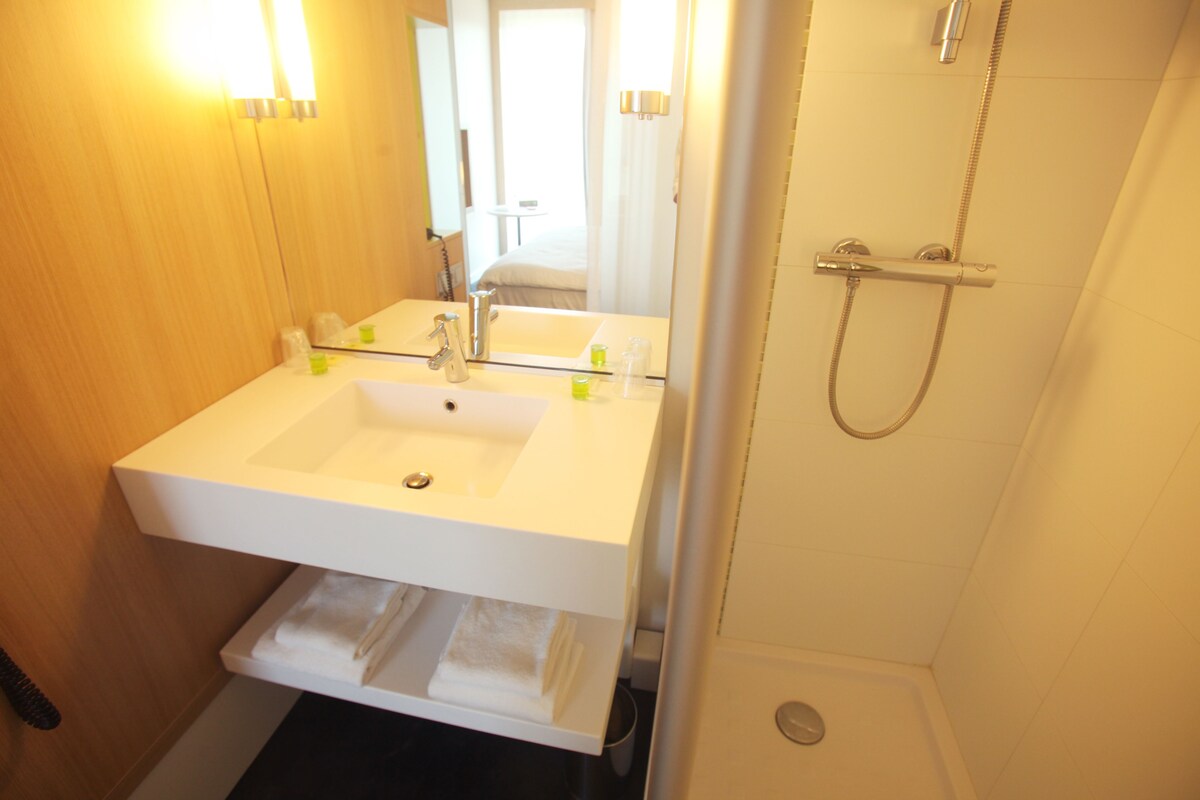 Une salle de bain avec un lavabo blanc, un miroir et une douche.