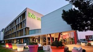 A modern hotel with a prominent 'ibis' sign, large potted plants, and a well-lit entrance. - ibis Styles Nantes Rezé Aéroport (Reze)