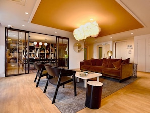 Un salon moderne avec un canapé marron, une table basse et un coin repas comprenant des chaises et une cloison en verre.