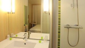 A modern bathroom with a large mirror, a sink, a shower, and a toilet. - ibis Styles Nantes Rezé Aéroport (Reze)